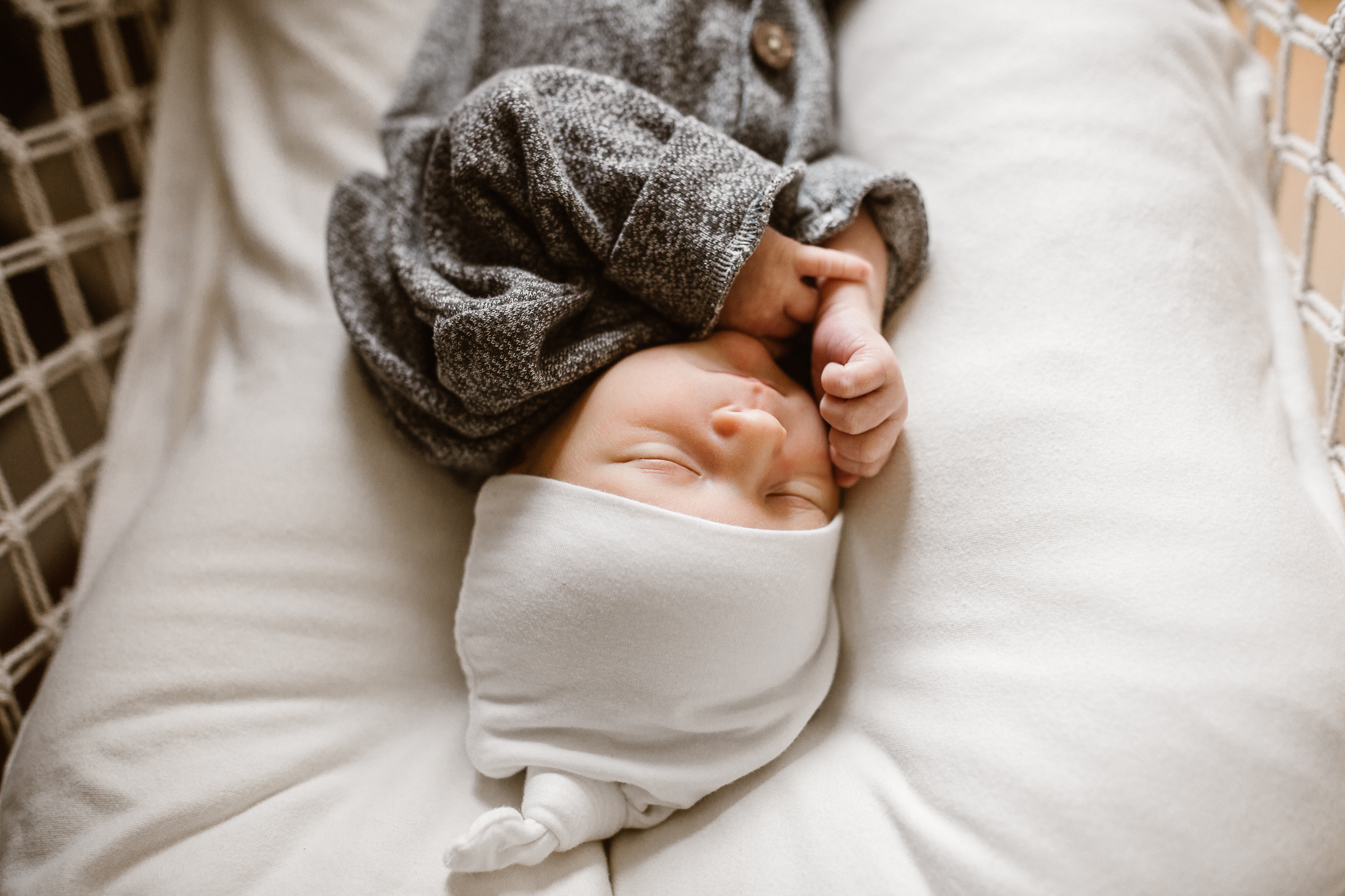 Newborn baby boy sleeping with a white hat on.
